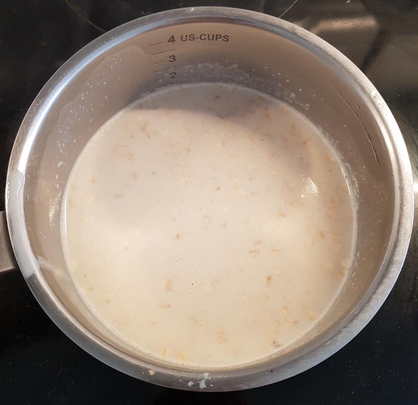 Lait et flocons versé dans une casserole, en cuisson à feu moyen 