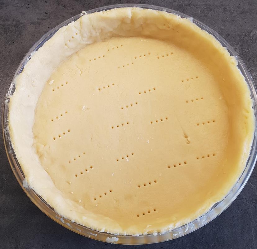 Pâte sucrée déposé dans un moule à tarte et piqué avec une fourchette avant cuisson